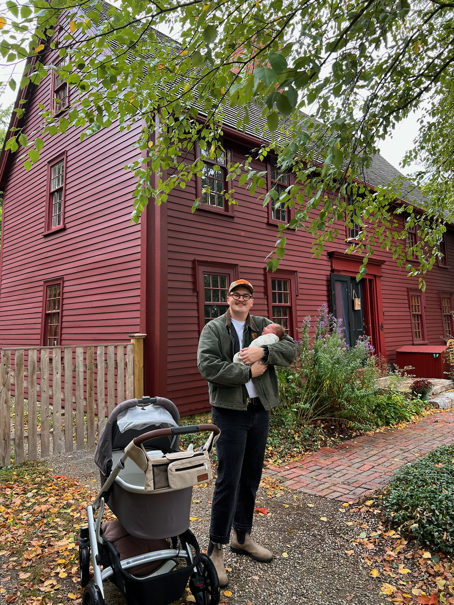 Jonathan with his baby outside an old red house in Ipswich